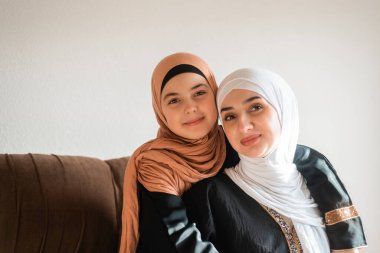 Mutlu Müslüman bir aile, anneler gününde şefkat gösterdikleri için kanepede sevgiyle sarılıyorlar. Yüksek kalite fotoğraf