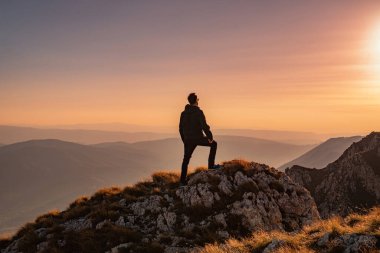 Yürüyüşe çıkan bir adam gün batımı macera yolculuğunda dağın tepesine bakmaktan zevk alır. Yüksek kalite fotoğraf
