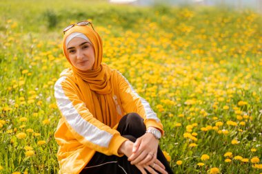 Çiçekli bir bahar tarlasında eğlenen genç ve mutlu bir Müslüman kadın. Yüksek kalite fotoğraf