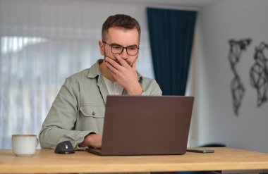 Evde çalışırken dizüstü bilgisayar kullanan endişeli bir adam. Yüksek kalite fotoğraf