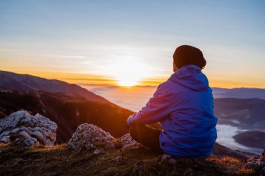 Huzurlu bir adam yoga yapıyor, doğa manzaralı bir dağın tepesinde tek başına dinleniyor. Yüksek kalite fotoğraf