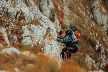 Erkek bir dağcı dağ kayalıklarına tırmanıyor. Adrenalin dolu maceralar yaşıyor. Açık havada. Yüksek kalite fotoğraf