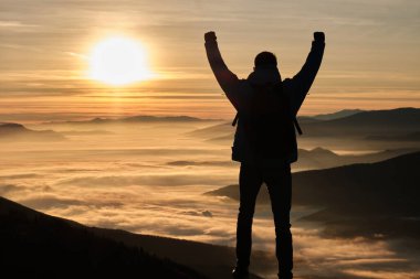 Mutlu bir yürüyüşçü, bir dağın tepesinde muhteşem bir gündoğumu ya da günbatımı macerasında başarıyı kutluyor. Aktif ve sağlıklı bir yaşam tarzı. Yüksek kalite fotoğraf