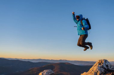 Dağ macerası yolculuğunun tepesinde zıplayan mutlu bir erkek yürüyüşçü. Yüksek kalite fotoğraf