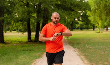 Sportif bir adam parkta koşuyor ya da koşuyor sağlıklı yaşam tarzı koşucusu ve akıllı saat kontrolü zamanı. Yüksek kalite fotoğraf
