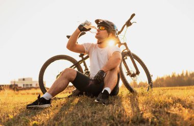 Profesyonel bir bisikletçi şişeden su içiyor. Aktif ve sağlıklı bir yaşam tarzı. Yüksek kalite fotoğraf