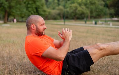 Spor yapan zinde bir adam yaz parkında oturur. Yüksek kalite fotoğraf