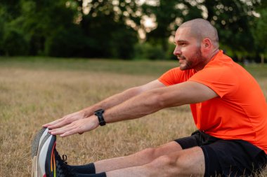 Sportif bir adam koşmadan önce esneme egzersizleri yapıyor ya da yaz parkında egzersiz yapıyor. Aktif, sağlıklı bir yaşam tarzı. - Evet. Yüksek kalite fotoğraf