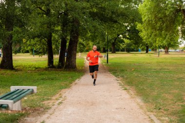 Sportif bir adam parkta koşuyor ya da koşuyor sağlıklı yaşam tarzı koşucusu ve akıllı saat kontrolü zamanı. Yüksek kalite fotoğraf
