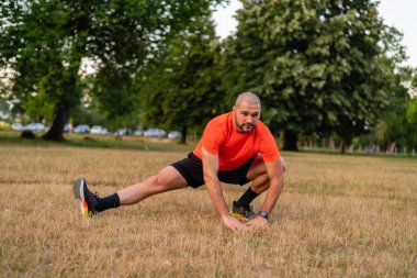 Sportif bir adam koşmadan önce esneme egzersizleri yapıyor ya da yaz parkında egzersiz yapıyor. Aktif, sağlıklı bir yaşam tarzı. - Evet. Yüksek kalite fotoğraf