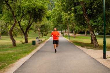 Sportif bir adam parkta koşuyor ya da koşuyor. Yüksek kalite fotoğraf
