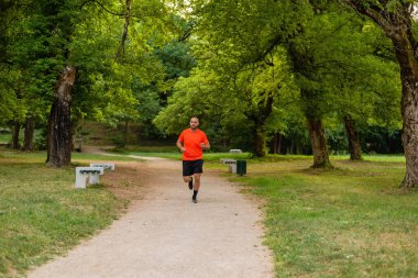 Sportif bir adam parkta koşuyor ya da koşuyor. Yüksek kalite fotoğraf