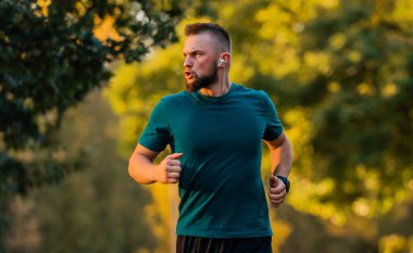 Genç bir sporcu parkta koşuyor ya da koşuyor. Aktif ve sağlıklı bir yaşam tarzı var. Yüksek kalite fotoğraf