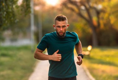 Sportif bir adam parkta koşuyor ya da koşuyor. Aktif, sağlıklı bir yaşam tarzı var. Yüksek kalite fotoğraf