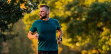 Genç bir sporcu parkta koşuyor ya da koşuyor. Aktif ve sağlıklı bir yaşam tarzı var. Yüksek kalite fotoğraf