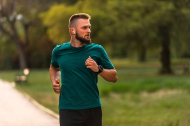 Genç atletik bir adam parkta koşuyor ya da koşuyor, aktif sağlıklı bir yaşam tarzı var. Yüksek kalite fotoğraf