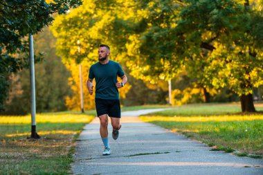 Genç bir sporcu parkta koşuyor ya da koşuyor. Aktif ve sağlıklı bir yaşam tarzı var. Yüksek kalite fotoğraf