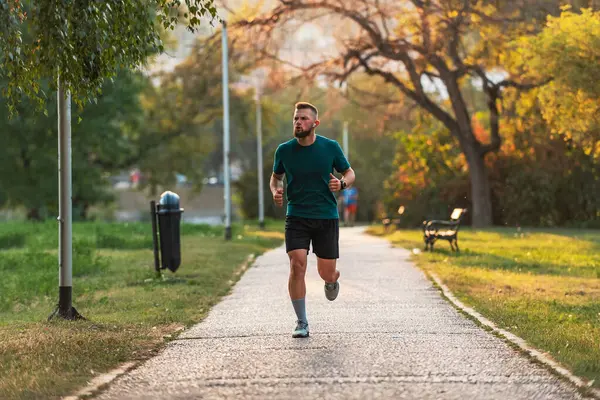 Genç bir sporcu parkta koşuyor ya da koşuyor. Aktif ve sağlıklı bir yaşam tarzı var. Yüksek kalite fotoğraf