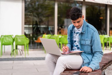 Bir erkek üniversite öğrencisi ya da bir kafede dizüstü bilgisayar kullanan serbest çalışan genç bir adam. Yüksek kalite fotoğraf