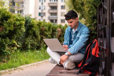 Erkek bir üniversite öğrencisi ya da dışarıda dizüstü bilgisayar kullanan genç bir adam. Yüksek kalite fotoğraf