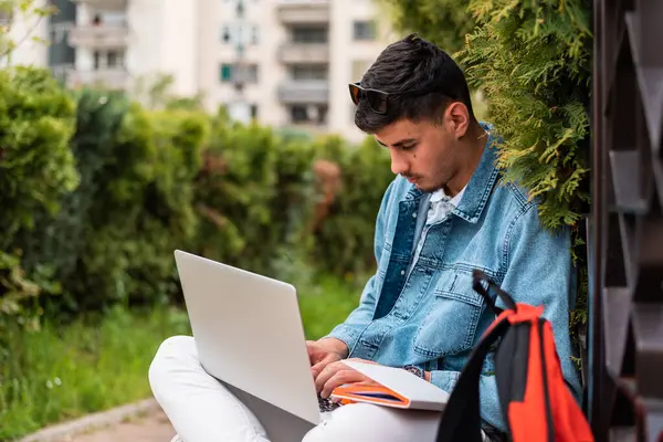 Erkek bir üniversite öğrencisi ya da dışarıda dizüstü bilgisayar kullanan genç bir adam. Yüksek kalite fotoğraf