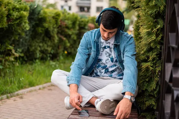 Dışarıda cep telefonu kullanan kulaklıklı genç bir adam. Yüksek kalite fotoğraf