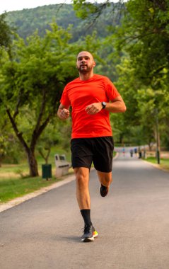 Sportif bir sporcu parkta koşuyor ya da koşuyor, aktif ve sağlıklı bir yaşam tarzı var. Yüksek kalite fotoğraf
