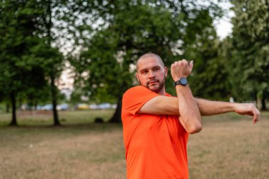 Sportif bir adam koşmadan önce esneme egzersizleri yapıyor ya da yaz parkında egzersiz yapıyor. Aktif, sağlıklı bir yaşam tarzı. - Evet. Yüksek kalite fotoğraf