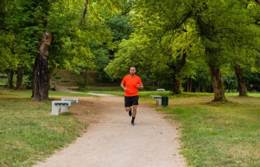 Sportif bir adam parkta koşuyor ya da koşuyor. Yüksek kalite fotoğraf
