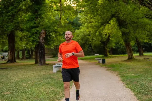 Sportif bir adam parkta koşuyor ya da koşuyor. Yüksek kalite fotoğraf