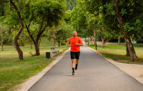 Sportif bir sporcu parkta koşuyor ya da koşuyor, aktif ve sağlıklı bir yaşam tarzı var. Yüksek kalite fotoğraf