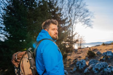 Dağ ormanı macerasında yürüyüş yapan mutlu bir sırt çantalı adam aktif bir hayat tarzında seyahat eder. Yüksek kalite fotoğraf