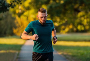 Genç atletik bir adam parkta koşuyor ya da koşuyor. Aktif, sağlıklı bir yaşam tarzı. Yüksek kalite fotoğraf