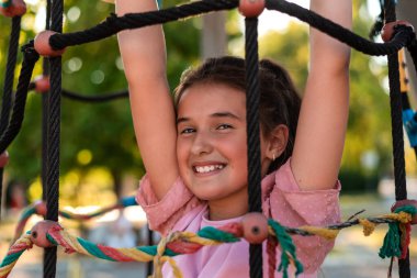 Parktaki parkta ipe tırmanan gülümseyen bir kız çocuğu. Yüksek kalite fotoğraf
