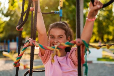 Parktaki parkta ipe tırmanan mutlu bir kız çocuğu. Yüksek kalite fotoğraf