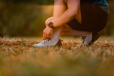 Koşu ayakkabıları bağlayan sportif bir adam parkta aktif yaşam tarzında koşuya ya da antrenmana hazırlanıyor. Yüksek kalite fotoğraf