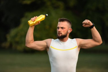 Başarılı bir koşudan ya da antrenmandan sonra formda olan genç bir adam yumruğunu kaldırıyor. Spor zaferi kavramı, zafer. Yüksek kalite fotoğraf