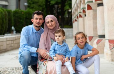 Şehir parkında kameraya bakıp gülümseyen mutlu bir müslüman ailenin portresi. Yüksek kalite fotoğraf