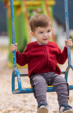 Küçük tatlı bir çocuk bir yaz parkında salıncakta sallanıyor. Yüksek kalite fotoğraf