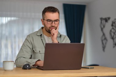 Evde çalışırken dizüstü bilgisayar kullanan genç bir adam. Yüksek kalite fotoğraf