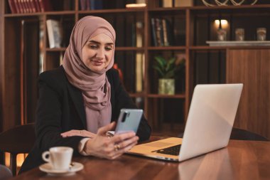 Ofiste çalışırken telefonunu kullanan mutlu bir Müslüman iş kadını. - Evet. Yüksek kalite fotoğraf