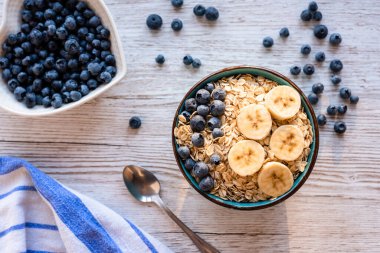 Yulaf, muz ve yaban mersinli sağlıklı bir kahvaltı. Kırsal ahşap bir masada, üst manzara. Yüksek kalite fotoğraf