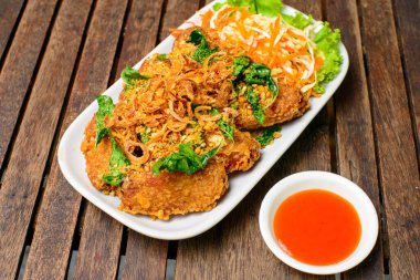 Kızarmış tavuk kanadı ve ahşap arka planda kızarmış bitki..