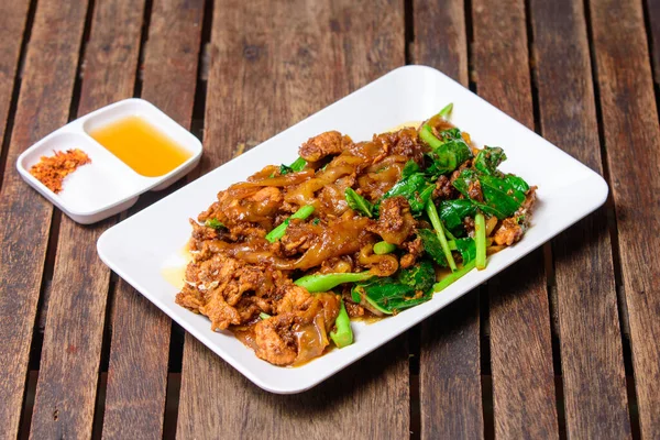 Soya soslu kızarmış pirinç eriştesi ve ahşap arka planda domuz eti..