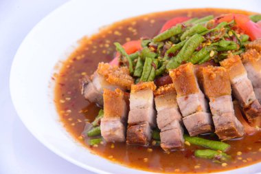 Kızarmış domuz eti, kıtır kıtır ve beyaz arka planda kırmızı köri..