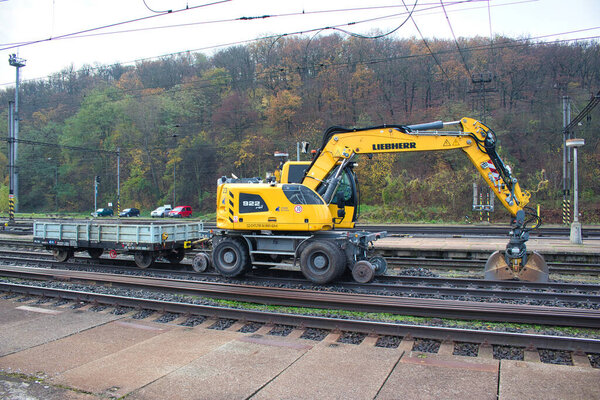 A yellow liebherr bagger 922 Rail at work close to platform. Czech Republic.