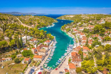 Hırvatistan 'ın Bra Adası' ndaki Bobovia na Moru 'nun insansız hava aracı görüntüsü, turkuaz Adriyatik suları, geleneksel taş evler, limandaki tekneler ve yaz aylarında yemyeşil Akdeniz manzaralı resim koyunu gösteriyor..