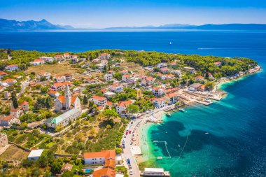 Hırvatistan 'ın Bra Adası' ndaki Zirvenin çarpıcı HDR insansız hava aracı görüntüsü, pitoresk köy merkezini, canlı rıhtımı, limandaki tekneleri ve ılık, huzurlu renklerle yıkanmış Akdeniz 'i gösteriyor..