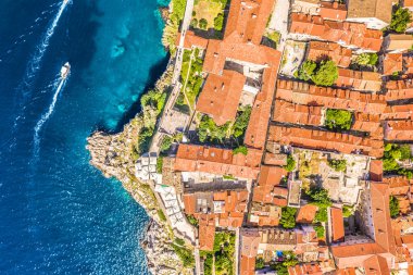 Dubrovniks 'in Eski Kent ve şehir duvarlarının dikey hava görüntüsü, tarihi mimarisini, dar sokaklarını ve UNESCO tarafından listelenen mirasını, derin mavi Adriyatik Denizi' nde ilerleyen yat ve sürat teknelerini gözler önüne seriyor..