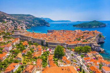 Tarihi duvarları ve kırmızı çatılarıyla Dubrovniks Eski Kasabası 'na bakan Pile Gate' in çarpıcı hava manzarası Adriyatik Denizi 'nin arka planında yer alan yemyeşil Lokrum adası,